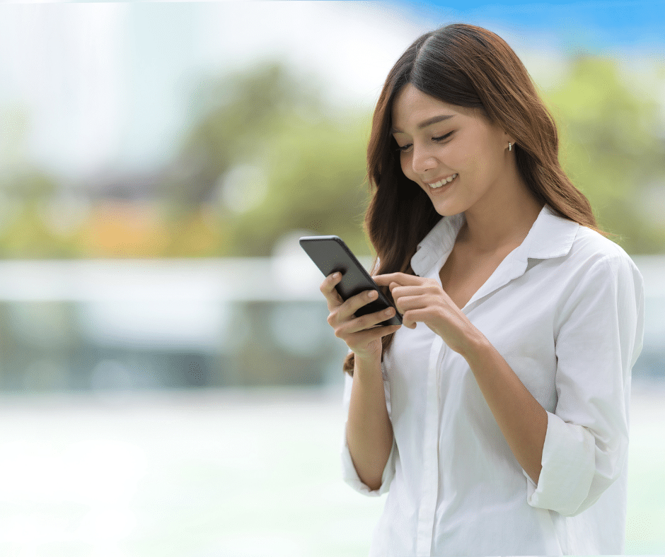 ผู้หญิงกำลังใช้โทรศัพท์มือถือและยิ้มด้วยึความสุข