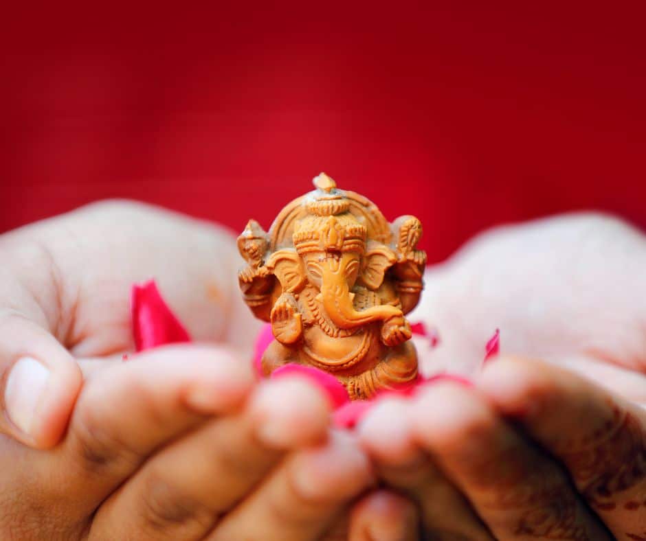 คนกำลังถือเทวรูปพระพิฆเนศไว้ในมือ