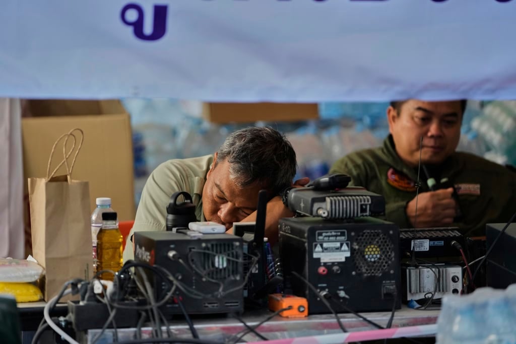 A radio operator rests after working overnight in his makeshift center at the site of an under-construction high-rise building that collapsed after an earthquake in Bangkok, Thailand, Monday, March 31, 2025.