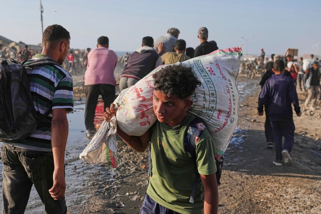 A Palestinian boy carries a sack of food and humanitarian aid unloaded from a World Food Program convoy that had been heading to Gaza City, in the northern Gaza Strip, Monday, June 16, 2025.