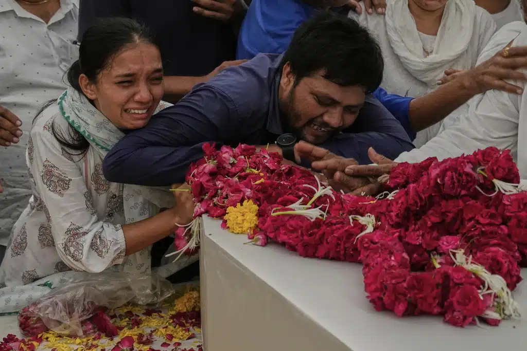 Relatives grieve near the coffins containing the remains of Rozar David Christian and his wife, Rachnaben Rozar Christian, both victims of the Air India plane crash, outside their home in Ahmedabad, India, Sunday, June 15, 2025