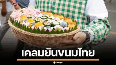 ภาพชายชาวต่างชาติในชุดที่ทำจากผ้ากรอมา กำลังถือตะกร้าขนมหน้าตาคล้ายขนมไทย