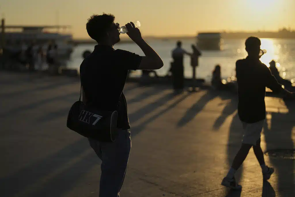 People drink water in a hot summer day at Kadikoy sea promenade, in Istanbul, Turkey, Wednesday, July 2, 2025.