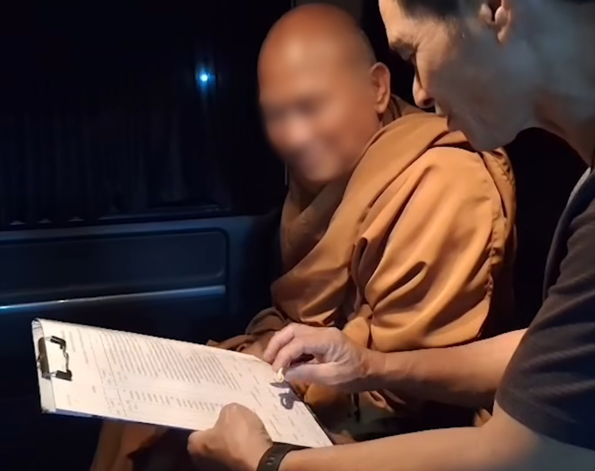 พระอลงกต ขณะอยู่บนรถยนต์พร้อมนั่งฟังเจ้าหน้าที่อ่านข้อหาตามหมายจับเมื่อวันที่ 22 สิงหาคม 2568