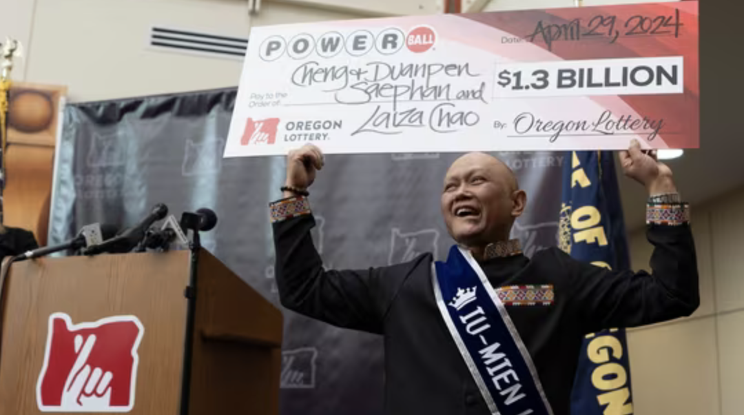 Cheng "Charlie" Saephan holds display check above his head after speaking during a news conference where it was revealed that he was one of the winners of the $1.3 billion Powerball jackpot at the Oregon Lottery headquarters on Monday, April 29, 2024, in Salem, Ore. (AP Photo/Jenny Kane)(AP)
