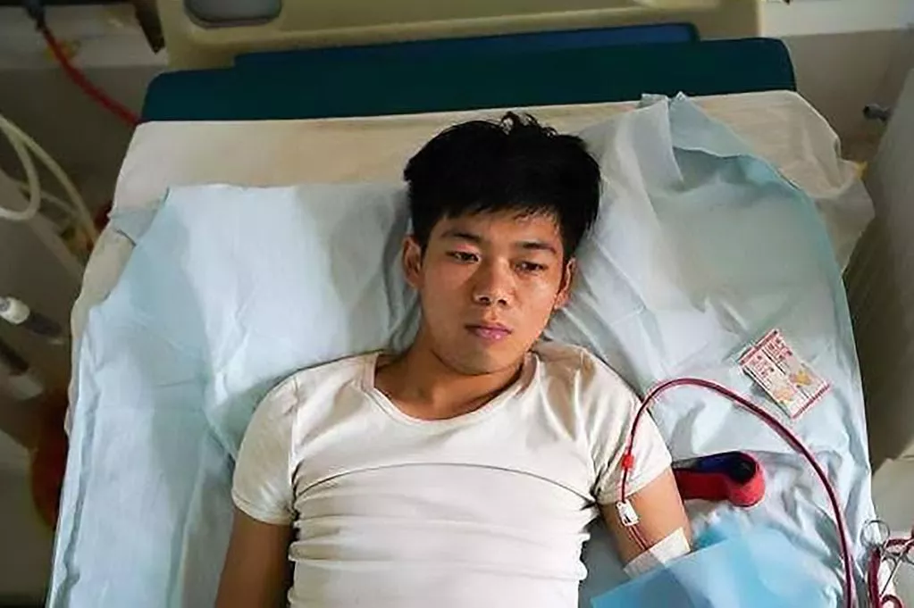 หวัง ช่างคุน นอนอยู่บนเตียงผู้ป่วยในโรงพยาบาลด้วยสีหน้าอิดโรย
