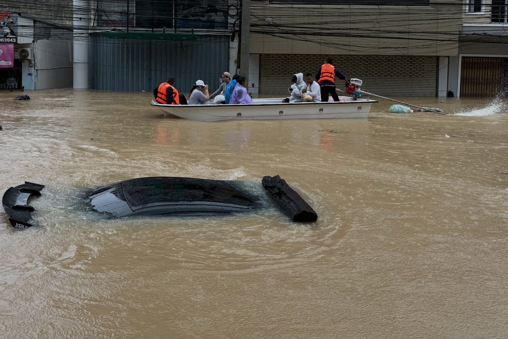 hai rescue crew on boat move past a car submerged in floodwaters in Songkhla province, southern Thailand, Monday, Nov. 24, 2025.