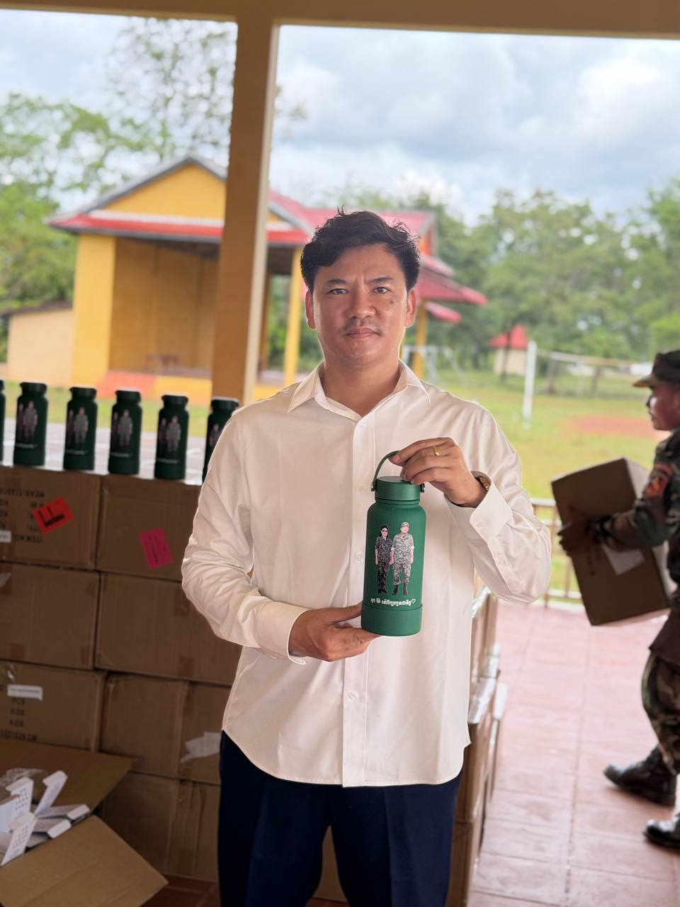 กระติกน้ำร้อนสีเขียวที่มีภาพของ ฮุน เซน และภริยาในเครื่องแบบทหาร