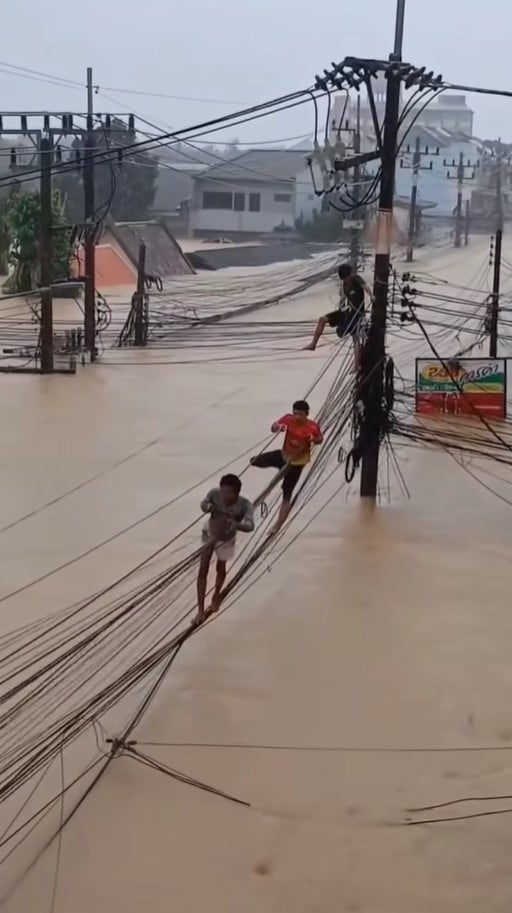 ชาวบ้านปีนอยู่บนสายไฟฟ้าและสายสื่อสารเหนือน้ำท่วม