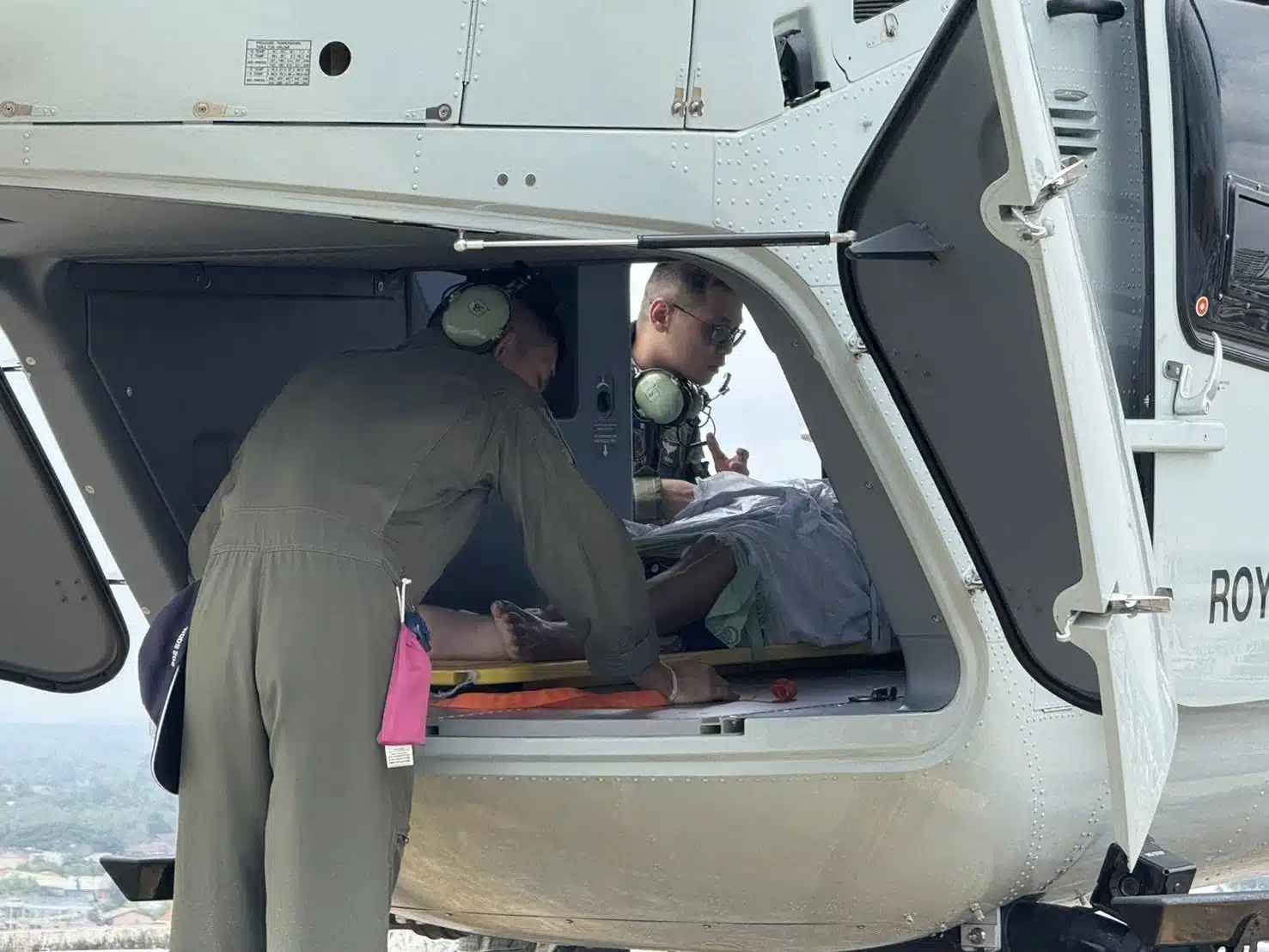 เจ้าหน้าที่ทหารอากาศกำลังช่วยกันเคลื่อนย้ายเปลผู้ป่วยขึ้นเฮลิคอปเตอร์