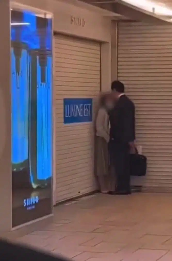 คู่รักยืนนัวเนียกันหน้าประตูเหล็กม้วน