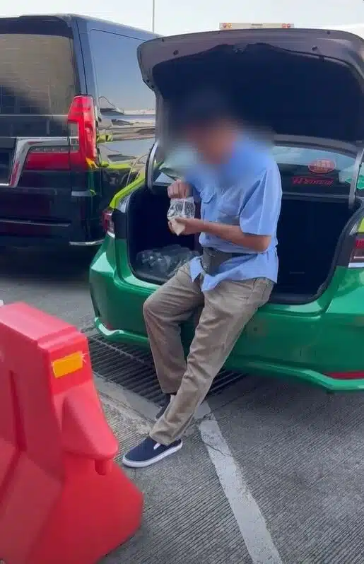 ภาพโชเฟอร์แท็กซี่กำลังยืนทานข้าวจากถุงพลาสติกท้ายรถ