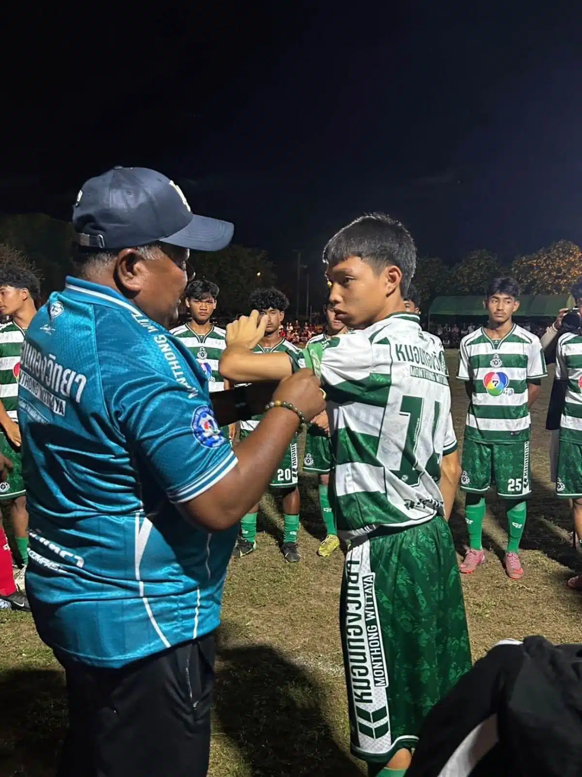 อาจารย์สกล กำลังสวมปลอกแขนกัปตันนทีมให้นักเรียนลูกทีม