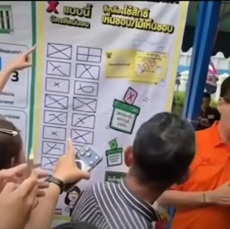 กลุ่มประชาชนชี้ไปที่ป้ายไวนิลเพื่อยืนยันความถูกต้อง