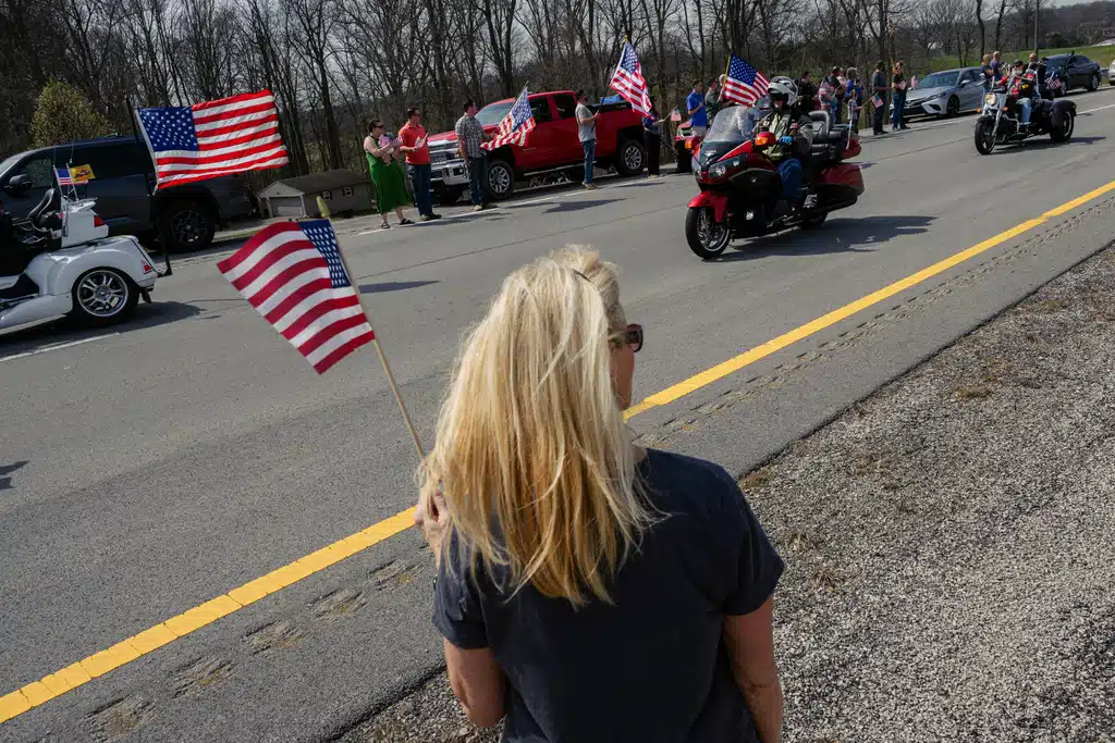 ประชาชนโบกธงชาติสหรัฐอเมริการอขบวนแห่ศพของสิบเอกเบนจามิน เอ็น. เพนนิงตัน อายุ 26 ปี จากเมืองเกลนเดล รัฐเคนตักกี้ ในวันศุกร์ที่ 20 มีนาคม 2026 ที่เมืองเอลิซาเบธทาวน์ รัฐเคนตักกี้