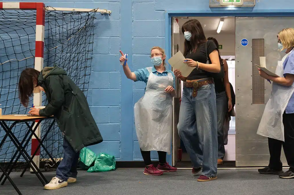 Students wait in line at the entrance to the sports hall at the University of Kent campus in Canterbury, England, Wednesday, March 18, 2026, where the rollout of a meningitis B vaccine to about 5,000 students has begun.