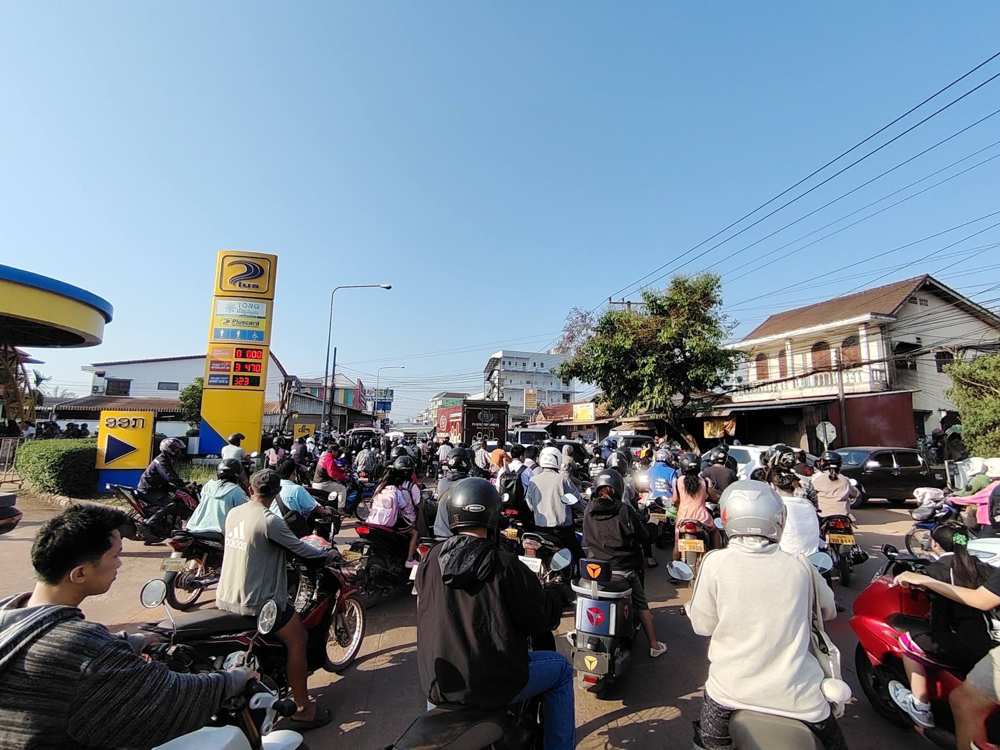 ประชาชนชาวลาวนำรถจักรยานยนต์มาต่อคิวรอเติมน้ำมันเชื้อเพลิง