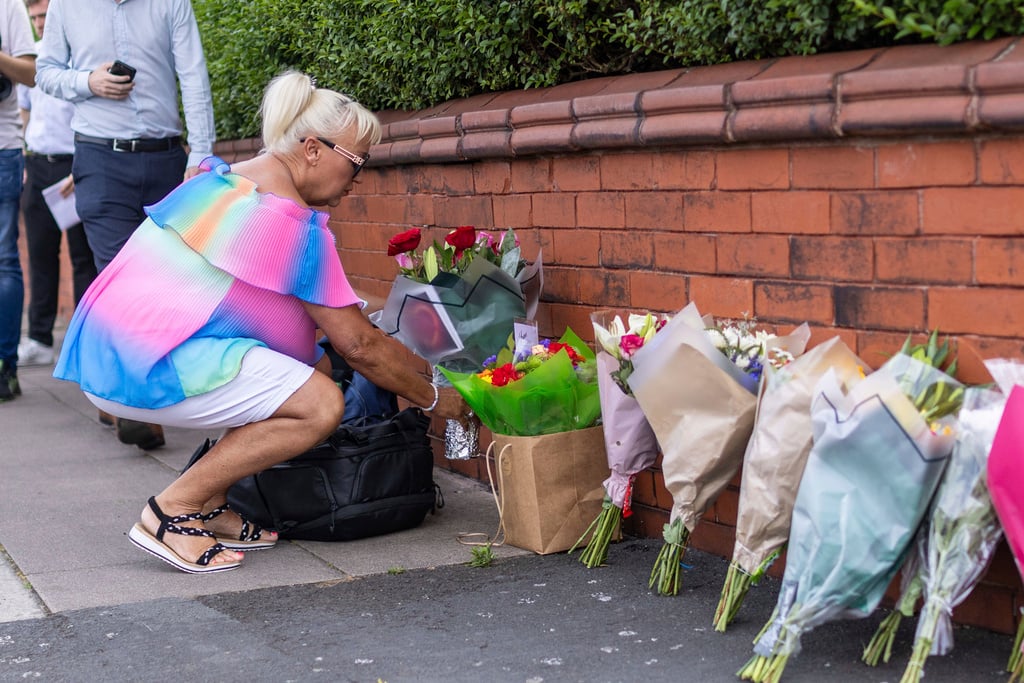 A person leaves flowers near the scene in Hart Street, Southport, Britain, Tuesday July 30, 2024, where two children died and nine were injured in a "ferocious" knife attack during a Taylor Swift event at a dance school on Monday. A 17-year-old male from Banks, Lancashire, has been arrested on suspicion of murder and attempted murder over the incident. 