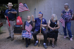 Roman Rena, center, waves a flag at a news conference where Officials with the League of United Latin American Citizens, or LULAC, held a news conference to respond to allegations by Texas Attorney General Ken Paxton, Monday, Aug. 26, 2024, in San Antonio. (AP Photo/Eric Gay).