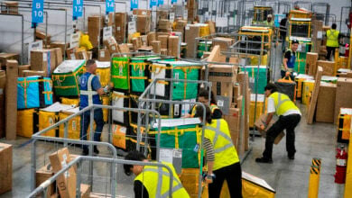 Amazon employees load packages on carts before being put on to trucks for distribution for Amazon's annual Prime Day event at an Amazon's DAX7 delivery station on July 16, 2024, in South Gate, Calif. Amazon reports earnings on Thursday, Aug. 1, 2024. (AP Photo/Richard Vogel, File)