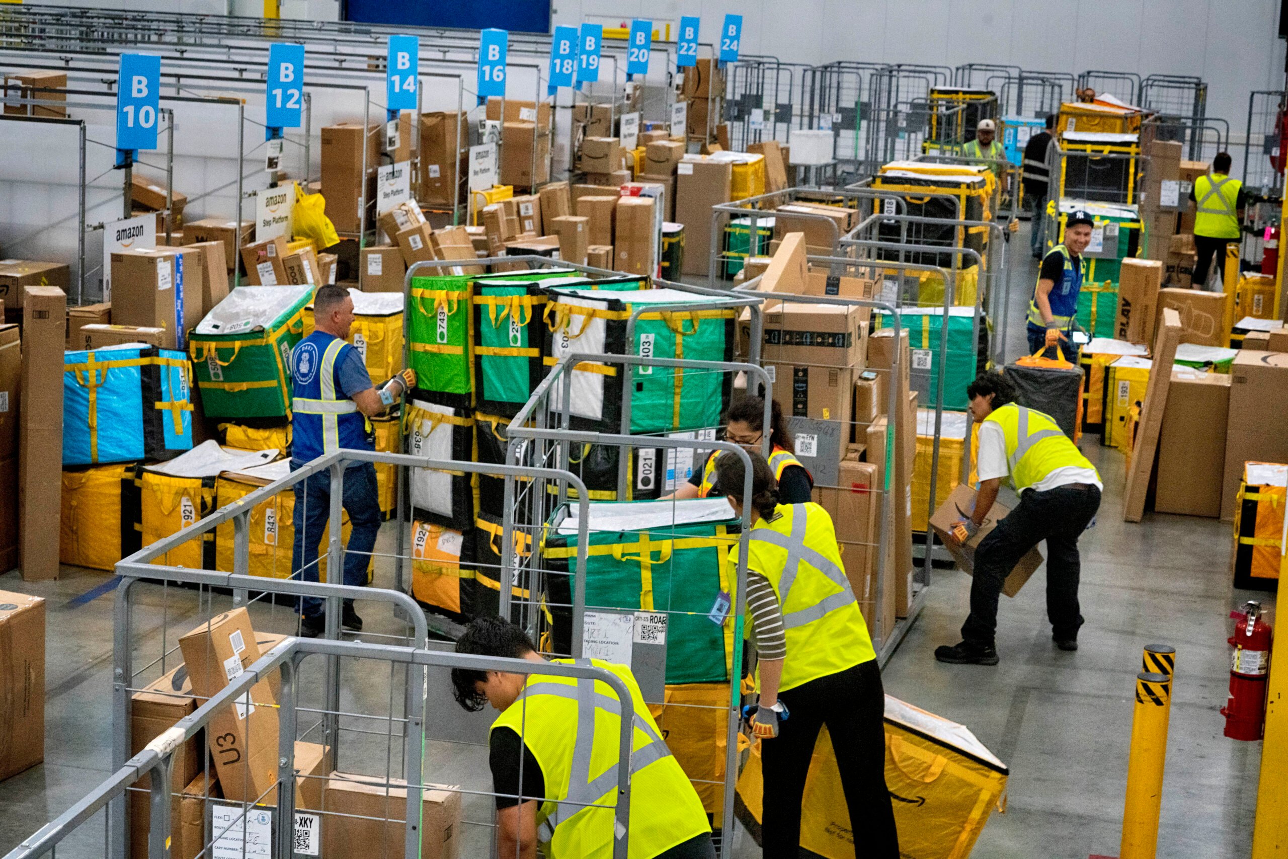 Amazon employees load packages on carts before being put on to trucks for distribution for Amazon's annual Prime Day event at an Amazon's DAX7 delivery station on July 16, 2024, in South Gate, Calif. Amazon reports earnings on Thursday, Aug. 1, 2024. (AP Photo/Richard Vogel, File)