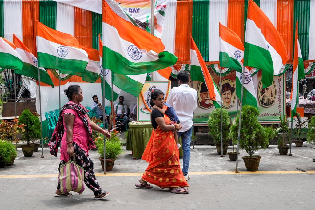 Commuters walk on a street decorated with Indian national flags during the country's Independence Day celebrations in Kolkata, India, Thursday, Aug. 15, 2024. (AP Photo/Bikas Das)