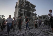 Palestinians stand in rubble after an Israeli airstrike in Deir al Balah, Gaza Strip, Tuesday, Aug. 6, 2024. (AP Photo/Abdel Kareem Hana)