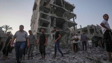 Palestinians stand in rubble after an Israeli airstrike in Deir al Balah, Gaza Strip, Tuesday, Aug. 6, 2024. (AP Photo/Abdel Kareem Hana)