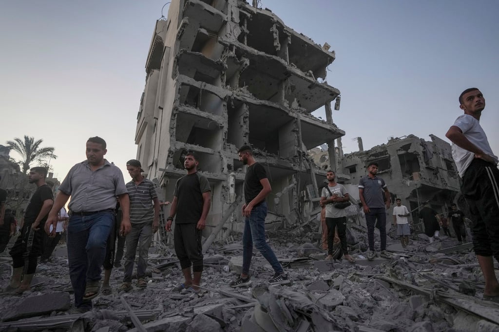 Palestinians stand in rubble after an Israeli airstrike in Deir al Balah, Gaza Strip, Tuesday, Aug. 6, 2024. (AP Photo/Abdel Kareem Hana)