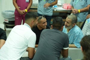 In this photo released by the Israel Prime Minister Office on Tuesday, Aug. 27, 2024, Qaid Farhan Alkadi, 52, right, who was held hostage by Hamas militants in Gaza sits in a room at the Soroka Medical Center in Beersheba, Israel. (Israel Prime Minister Office via AP).