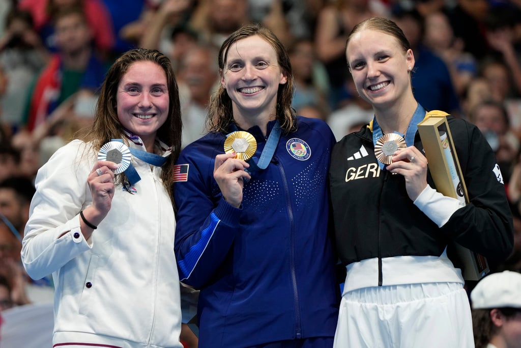 Gold medalist Katie Ledecky, center, of the United States, silver medalist Anastasiia Kirpichnikova, left, of France, and bronze medalist Isabel Gose, of Germany, pose for a photo following the women's 1500-meter freestyle final at the 2024 Summer Olympics, Wednesday, July 31, 2024, in Nanterre, France.