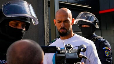 Andrew Tate flanked by masked gendarmes is led for questioning after a police search raid on his residence, on the outskirts of Bucharest, Romania, Wednesday, Aug. 21 2024. Masked police officers in Romania carried out fresh raids early Wednesday at the home of divisive internet influencer Andrew Tate, who is awaiting trial on charges of human trafficking, rape and forming a criminal gang to sexually exploit women. (AP Photo/ Vadim Ghirda).