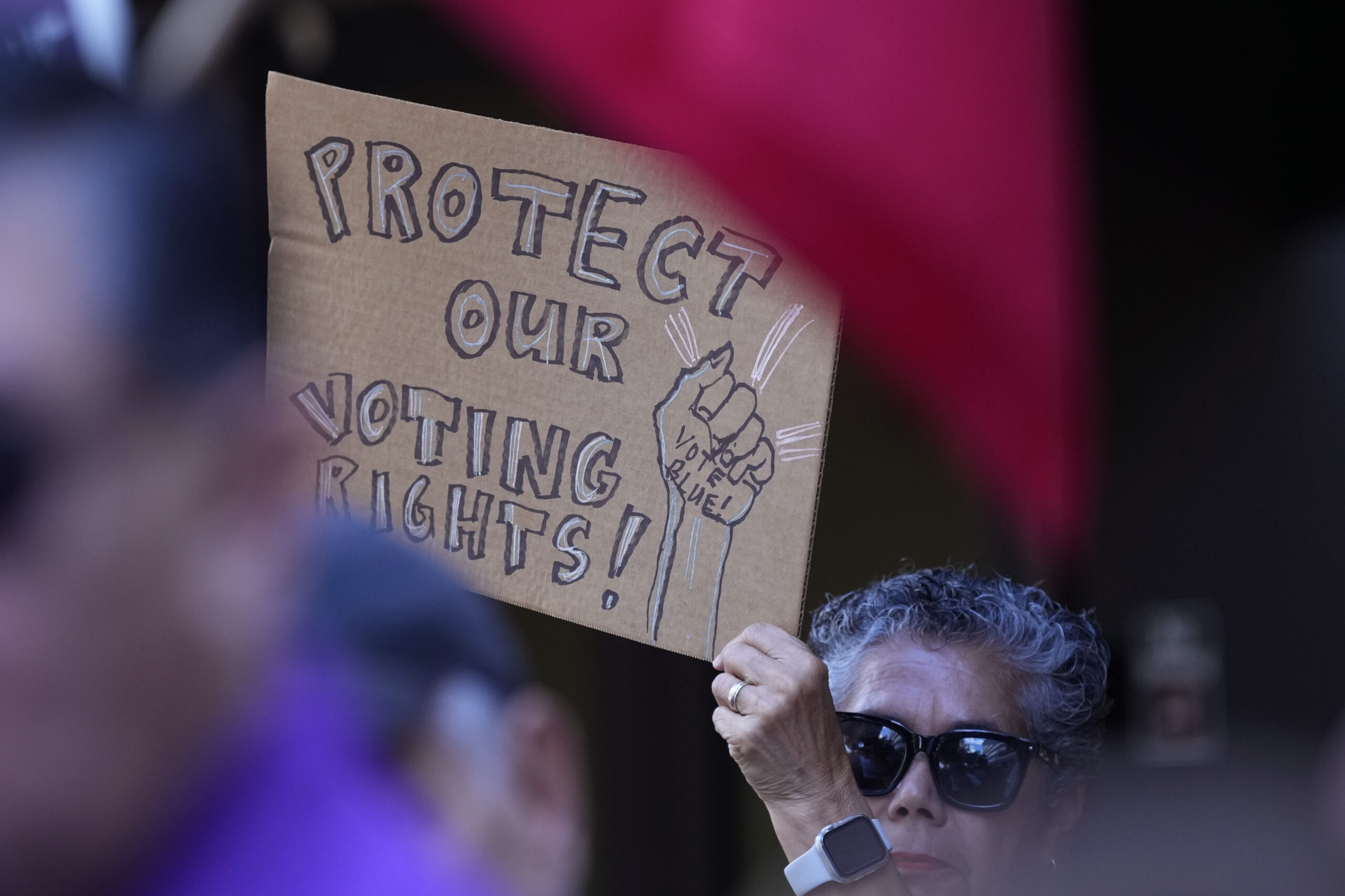 A supporter waves a sign at a news conference where Officials with the League of United Latin American Citizens, or LULAC, held a news conference to respond to allegations by Texas Attorney General Ken Paxton, Monday, Aug. 26, 2024, in San Antonio. (AP Photo/Eric Gay).