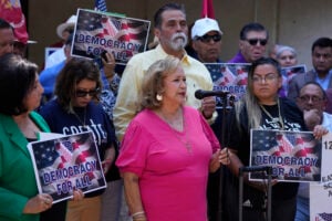 Lydia Martinez, a volunteer and great-grandmother whose home was searched, center, speaks at a news conference where she and officials with the League of United Latin American Citizens, or LULAC, responded to allegations by Texas Attorney General Ken Paxton, Monday, Aug. 26, 2024, in San Antonio. (AP Photo/Eric Gay).