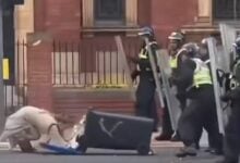 Woman charged after pushing wheelie bin at police in UK riots