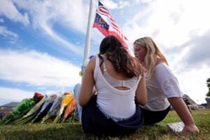 Two students view a memorial as the flags fly half-staff after a shooting Wednesday at Apalachee High School, Thursday, Sept. 5, 2024, in Winder, Ga. (AP Photo/Mike Stewart).