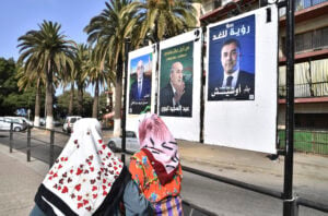 Women walk past electoral banners of presidential candidate, including President Abdelmadjid Tebboune, center, Tuesday, Aug. 27, 2024, in Algiers, Algeria. (AP Photo/Fateh Guidoum).