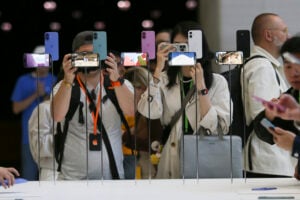 Attendees take a closer look at the Apple iPhone 16 during an announcement of new products at Apple headquarters Monday, Sept. 9, 2024, in Cupertino, Calif. (AP Photo/Juliana Yamada).