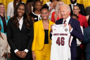 President Joe Biden, right, holds up a jersey that was presented to him by University of South Carolina Women's basketball team members Bree Hall, left, and Te-Hina Paopao, center, during an event in the East Room of the White House in Washington, Tuesday, Sept. 10, 2024, to celebrate their 2023-2024 NCAA championship season. (AP Photo/Susan Walsh).