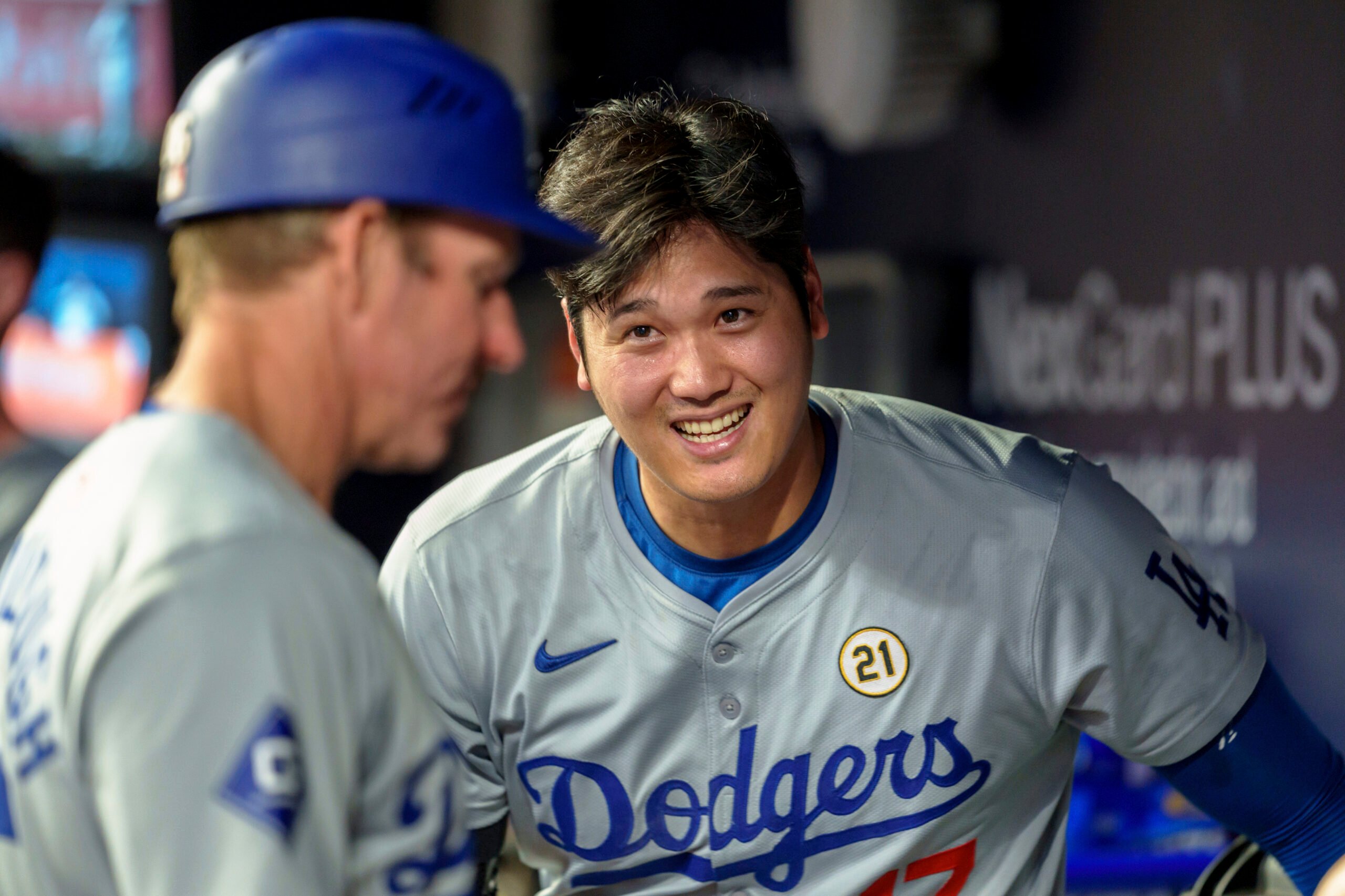 Los Angeles Dodgers two-way player Shohei Ohtani laughs with teammates in the dugout in the ninth inning of a baseball game against the Atlanta Braves, Sunday, Sept. 15, 2024, in Atlanta. (AP Photo/Jason Allen).