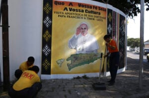 People clean a street next to a banner to welcome Pope Francis in Dili, East Timor Friday, Sept. 6, 2024. (AP Photo/Firdia Lisnawati).