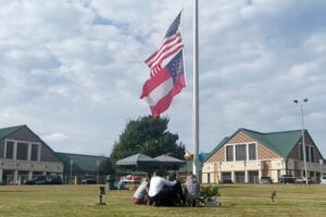 People gather at the flagpole outside the entrance to Apalachee High School on Thursday, Sept. 5, 2024 in Winder, Ga.,  a day after deadly shootings at the school.  (AP Photo/Sharon Johnson).