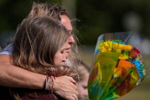 People embrace at a makeshift memorial after a shooting Wednesday at Apalachee High School, Thursday, Sept. 5, 2024, in Winder, Ga. (AP Photo/Mike Stewart).