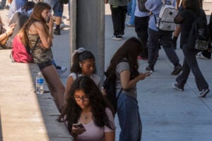 Students use their cellphones as they leave for the day the Ramon C. Cortines School of Visual and Performing Arts High School in downtown Los Angeles, Aug. 13, 2024. (AP Photo/Damian Dovarganes, File).