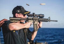 This undated photo, provided by Stars and Stripes, shows Cameron Yaste, commanding officer of the destroyer USS John McCain, firing a rifle with a backwards scope. (Stars and Stripes/Stars and Stripes via AP).