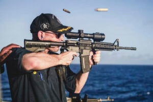 This undated photo, provided by Stars and Stripes, shows Cameron Yaste, commanding officer of the destroyer USS John McCain, firing a rifle with a backwards scope. (Stars and Stripes/Stars and Stripes via AP).