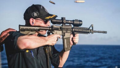 This undated photo, provided by Stars and Stripes, shows Cameron Yaste, commanding officer of the destroyer USS John McCain, firing a rifle with a backwards scope. (Stars and Stripes/Stars and Stripes via AP).