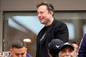 Elon Musk talks to other spectators while watching play between Jannik Sinner, of Italy, and Taylor Fritz, of the United States, during the men's singles final of the U.S. Open tennis championships, Sunday, Sept. 8, 2024, in New York. (AP Photo/Kirsty Wigglesworth).