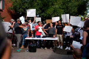 Resident Jaun Carlos Jimenez, center left, listens as Jeraldine Mazo, center right, speaks during a rally staged by the East Colfax Community Collective to address chronic problems in the apartment buildings occupied by people displaced from their home countries in central and South America Tuesday, Sept. 3, 2024, in Aurora, Colo. (AP Photo/David Zalubowski).