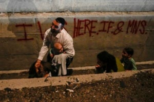 People take cover on the side of the road as a siren sounds a warning of incoming missiles fired from Iran on a freeway in Shoresh, between Jerusalem and Tel Aviv in Israel Tuesday, Oct. 1, 2024. (AP Photo/Ohad Zwigenberg).